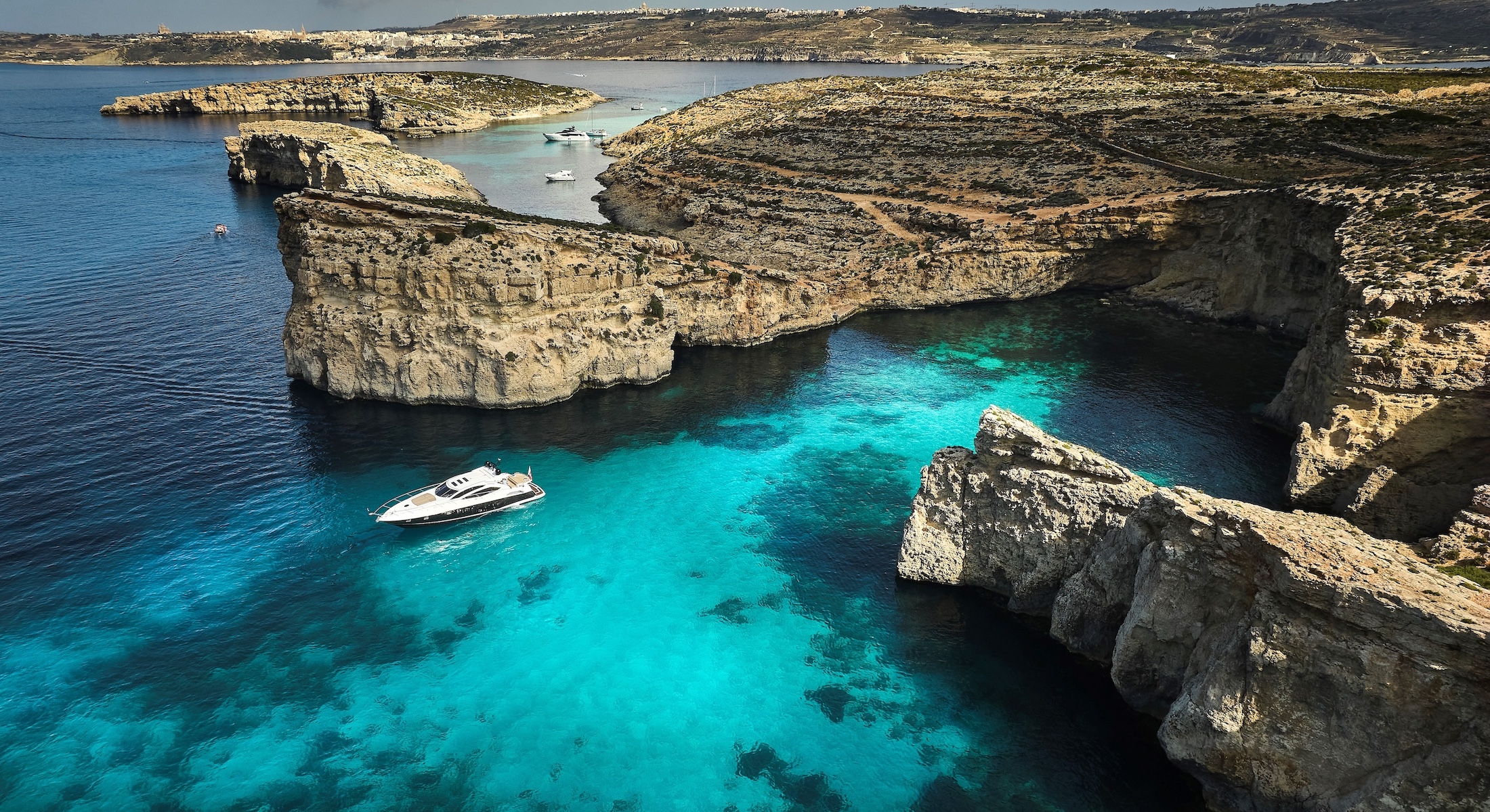 Yacht fuq l-ilma turkiż tal-Blue Lagoon ta' Kemmuna